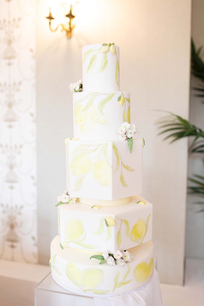 Five-tier white wedding cake with hand-painted lemons, pale lemon leaves and sugarpaste cherry blossoms