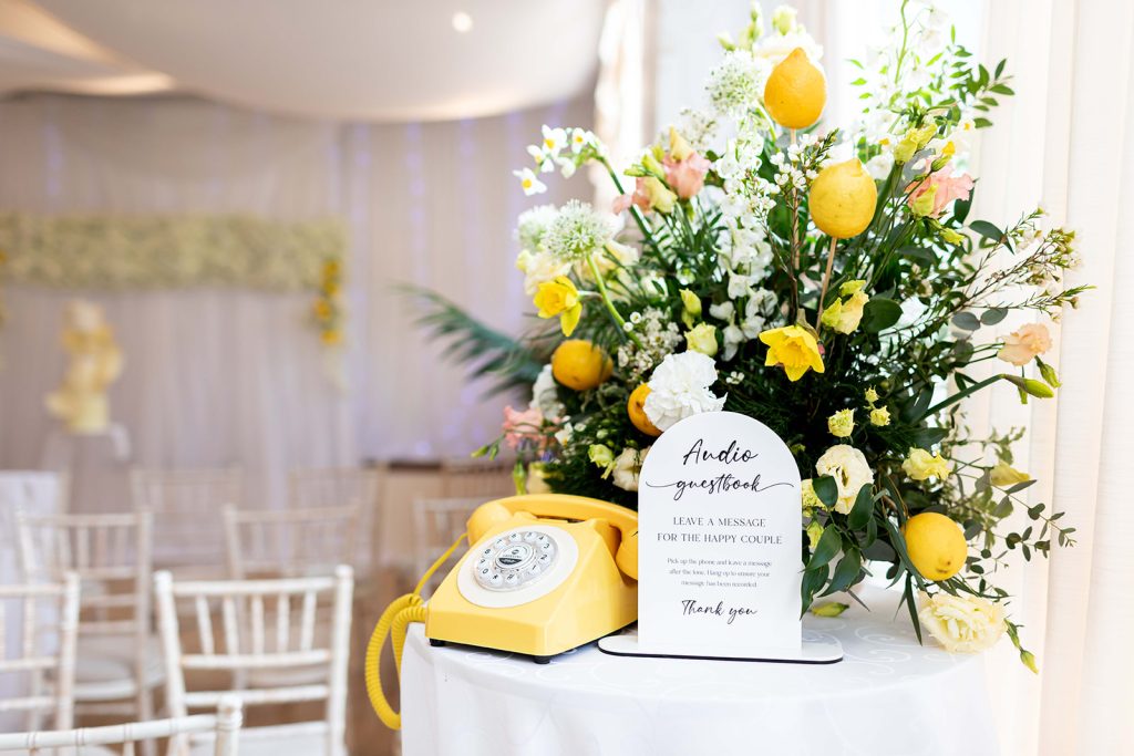 Yellow wedding floral display with vintage telephone guest audio book on table
