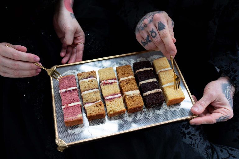 Couple enjoying a bespoke wedding cake tasting on antique lace tray with gold forks